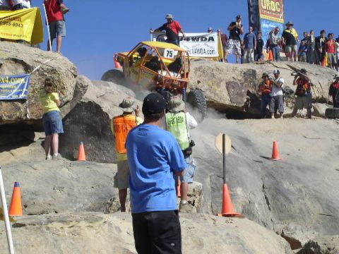1979 Ford Bronco - An off-road buggy navigates a steep, rocky incline during a competition, with spectators watching from above.