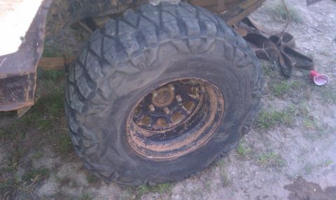 1979 Ford Bronco - A close-up view of a heavily used off-road tire and wheel, showing mud and wear.