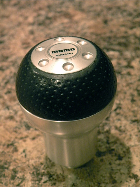 2006 Subaru Legacy - Close-up of a Momo shift knob, the Subaru branding on its silver top plate.