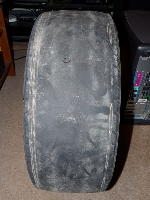 2006 Ford E350 - Straight-on tread view of a wide performance tire worn completely smooth across the center, with only the outer shoulder sipes and faint we…