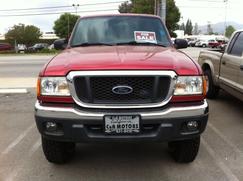 1993 Ford Taurus - A red Ford Ranger pickup truck is parked in front of a dealership, with a 'For Sale' sign displayed on its windshield.