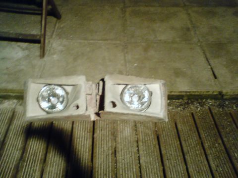 1989 Ford Bronco - A pair of headlights are shown resting on a slatted wooden surface.
