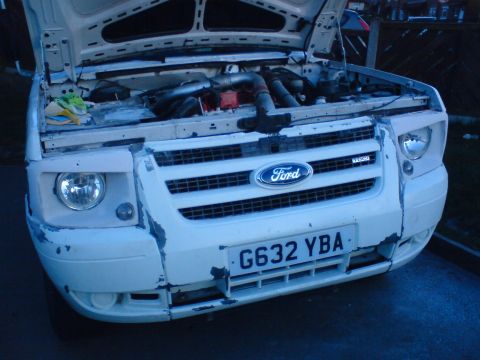 1989 Ford Bronco - Front view of a white Ford Transit van with the hood up, revealing the engine bay.