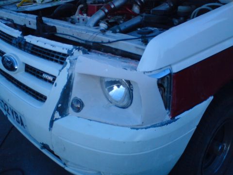 1989 Ford Bronco - The front end of a Ford truck appears to be undergoing modifications, with the hood open and engine components visible.