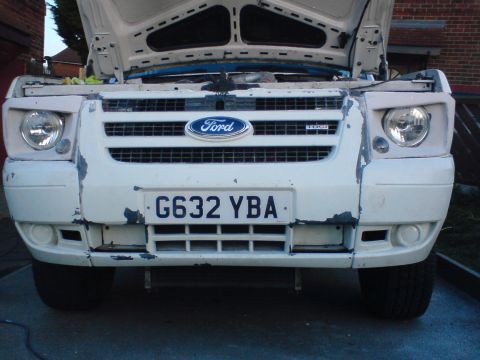 1989 Ford Bronco - Front view of a white Ford Transit van with its hood open, revealing a worn bumper and grille.