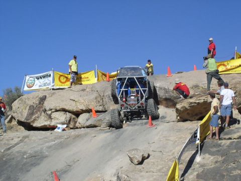 1979 Ford Bronco - A custom off-road vehicle navigates a challenging rocky terrain during an event, with spectators watching from the sidelines.
