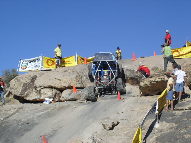 Off-road vehicle with roll cage climbing rocks, number 180 visible