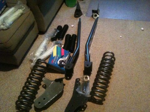 1993 Ford Bronco - Various automotive suspension components are arranged on the floor, ready for installation.