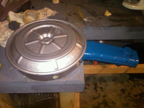 1979 Ford Bronco - A silver air cleaner assembly sits next to a freshly painted blue intake manifold on a workbench.