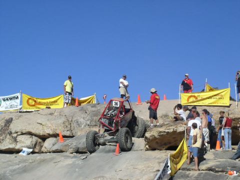 1979 Ford Bronco - An off-road buggy competes on a challenging rocky terrain under a clear blue sky.