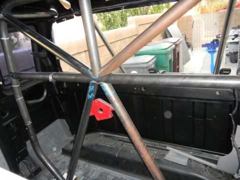 1997 Ford Ranger - A roll cage is being installed inside a vehicle, with blue markings on the metal tubes for welding.