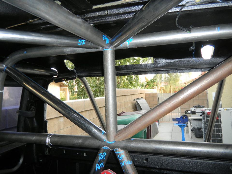 Interior view of a custom roll cage with blue markings and 'TOP PASS' and 'TOP DRIVER' labels