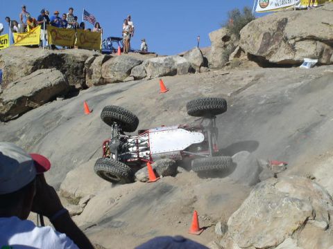 1979 Ford Bronco - An off-road buggy has overturned while navigating a steep, rocky course, with spectators observing the event.