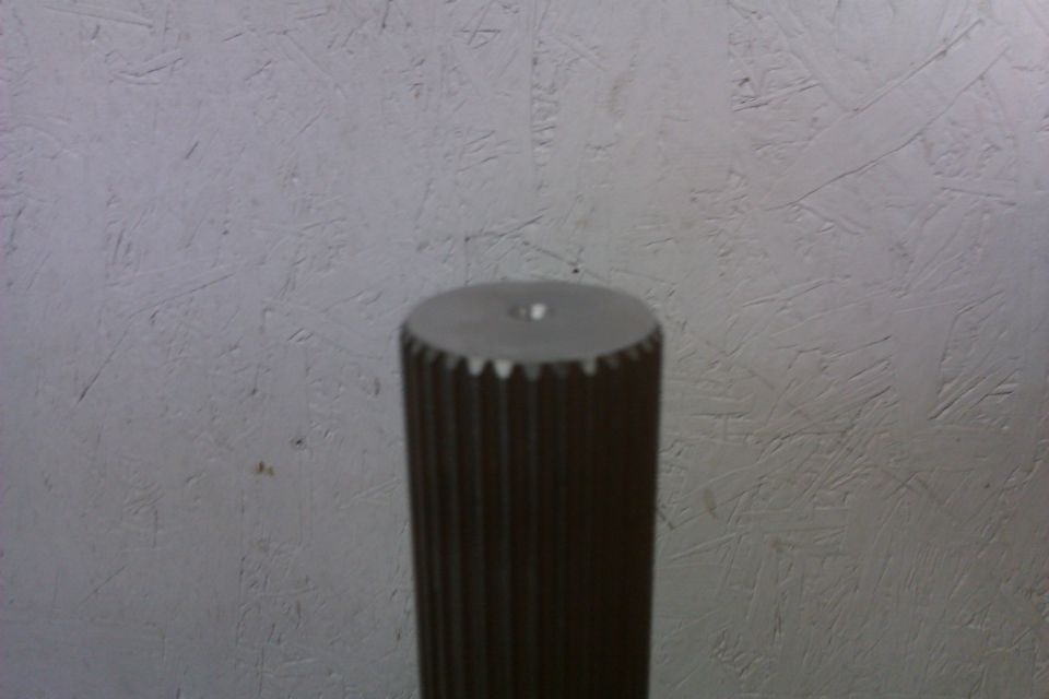 Splined shaft with a hole in the center, against a textured gray background