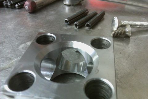 1999 Chevrolet Camaro - A close-up view of a machined metal component with fasteners and pins, likely for mechanical assembly.