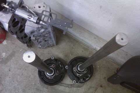 1999 Chevrolet Camaro - Axle shafts and brake assemblies are laid out on the floor next to engine components and a rotary tool.