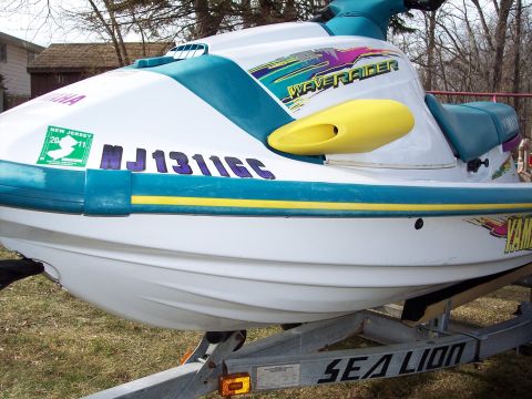 1996 Yamaha RA760 WaveRaider 2-P - A white and teal jet ski with yellow accents is parked on a trailer.