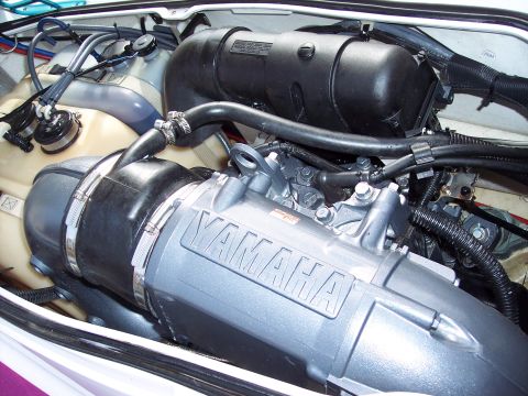 1996 Yamaha RA760 WaveRaider 2-P - Close-up view of the engine compartment of a personal watercraft, showing various mechanical parts and tubing.