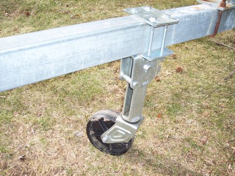 1996 Yamaha RA760 WaveRaider 2-P - Close-up of a trailer jack wheel and its mounting hardware on a grassy surface.