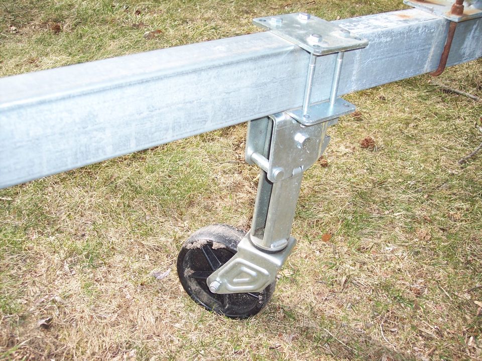 Galvanized boat-trailer frame with a swing-down swivel jack wheel on grass