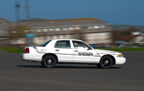 2001 Ford Crown Victoria - A white 2001 Ford Crown Victoria police car, marked 'WASHINGTON COUNTY SHERIFF', is captured in motion from the side.