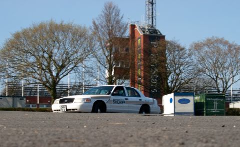 2001 Ford Crown Victoria - A sheriff's car is parked in front of a brick building with a radio tower.