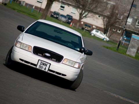 2001 Ford Crown Victoria - A white 2001 Ford Crown Victoria is captured in a 3/4 front view, displaying its license plate.
