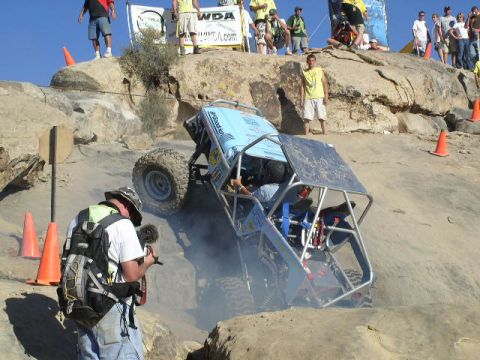 1979 Ford Bronco - A custom off-road buggy navigates a steep, sandy, and rocky incline during a competition.