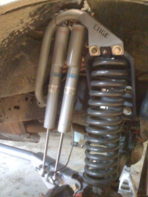 1995 Ford Bronco - Custom suspension setup with dual shocks and a coilover spring, a 'CAGE' bracket.