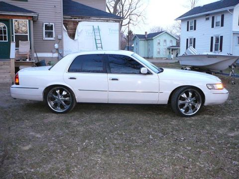 1999 Mercury Grand Marquis - A white 1999 Mercury Grand Marquis is shown from the side, custom chrome wheels.