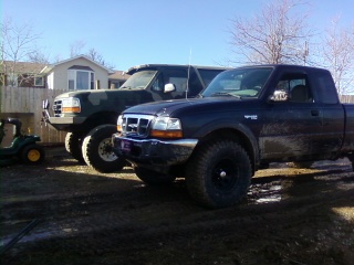 1995 Ford Bronco - Two Ford trucks, a Ranger and a Bronco, are parked side-by-side in a dirt lot under a clear sky.