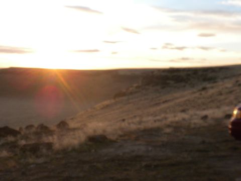 1989 Ford Bronco - Sunset over a dusty landscape with a car in the distance.