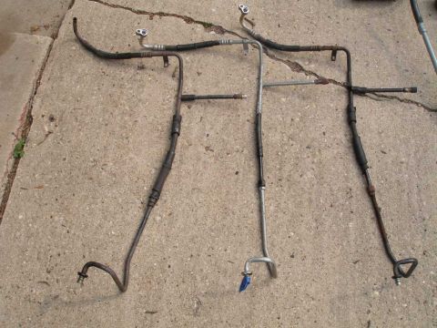 1997 Ford Taurus - Three AC hoses are shown on a concrete surface, likely for a vehicle repair or sale.