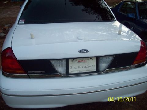 1998 Ford Crown Victoria - Rear view of a white Ford Crown Victoria with two short white antenna mounts standing on the trunk lid, a Ford oval badge between the rever…