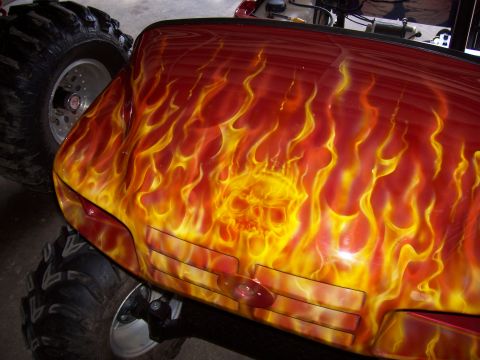1978 Ford F-150 - Custom airbrushed truck flames and a skull design, equipped with large off-road tires.