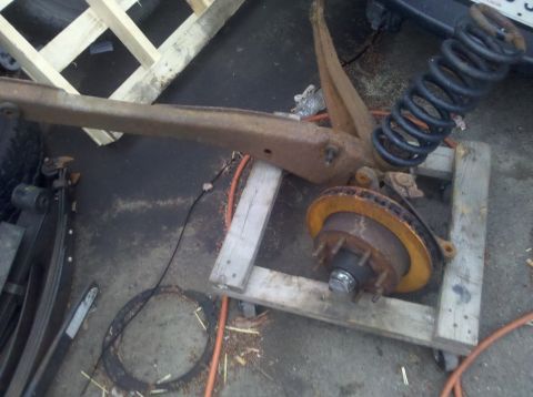 2003 Ford F-250 - Disassembled vehicle suspension component with brake rotor and coil spring.