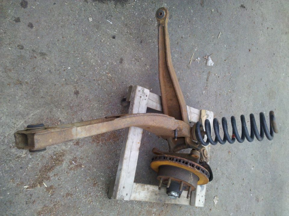 Front suspension assembly with coil spring and brake rotor, resting on wooden blocks