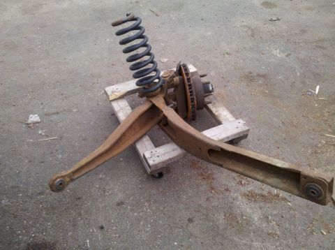 2003 Ford F-250 - A single rusty front suspension part, including a coil spring and brake rotor, rests on a wooden pallet.