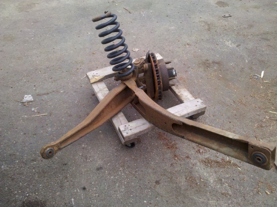 Rusty front suspension assembly with coil spring and brake rotor on a wooden pallet