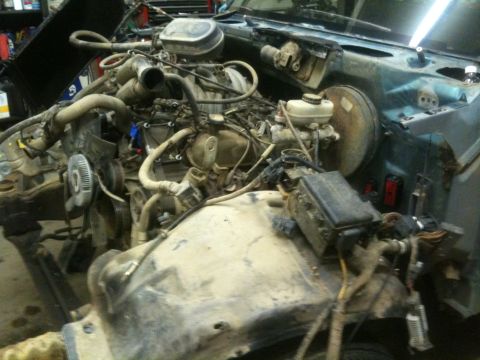 1993 Ford Bronco - The engine bay of a vehicle is shown disassembled, with numerous hoses, wires, and engine components visible.