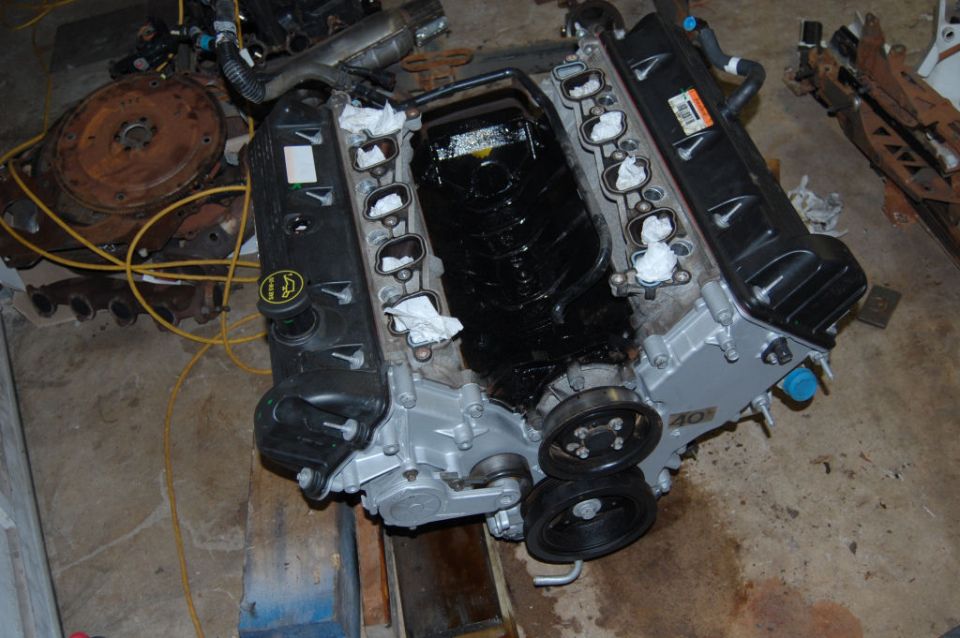 Engine block with intake manifold removed, showing internal components. Parts and wiring are scattered around