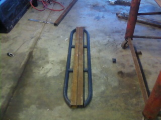 1995 Ford Bronco - Rock sliders with wooden planks are shown on a concrete floor.