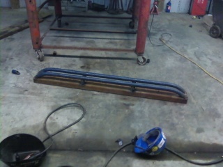 1995 Ford Bronco - A pair of custom rock sliders are shown mounted on a wooden base, ready for installation.