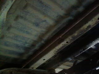 1995 Ford Bronco - Close-up view of the underside of a vehicle frame, showing structural components and wear.