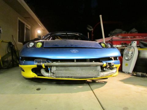 1995 Ford Probe - A blue sports car with a prominent intercooler and yellow trim is shown from the front in a garage setting.