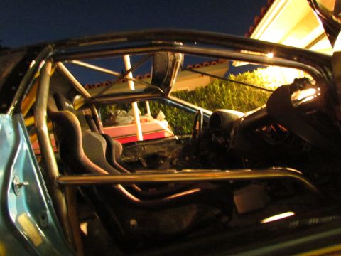 1995 Ford Probe - The interior of a modified vehicle features a prominent roll cage and racing seats, with a glimpse of its blue exterior.