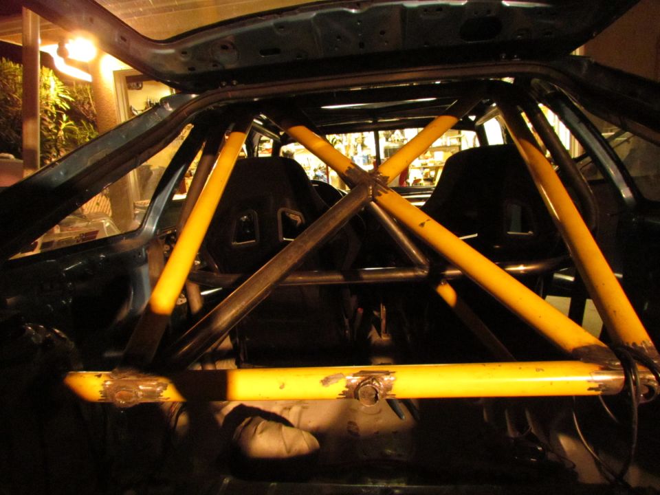 Interior view of a car with a yellow roll cage and racing seats