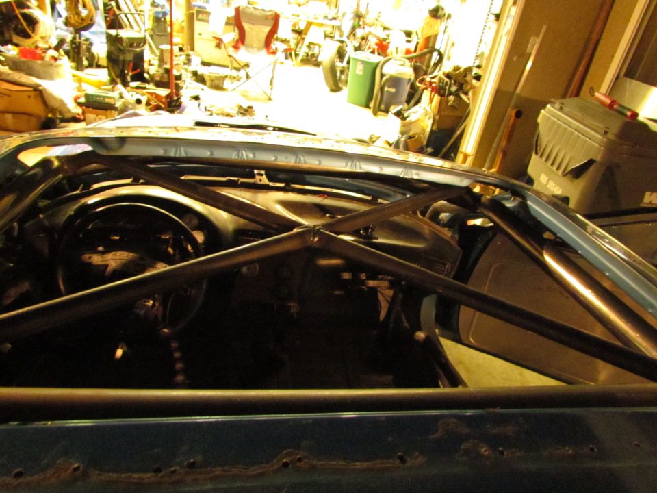 Blue car interior with a black roll cage, dashboard, and steering wheel visible