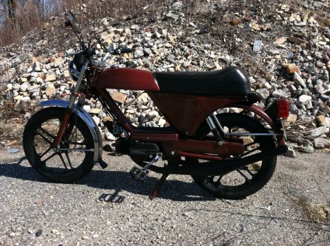 1981 Garelli Rally Sport - A red moped is parked on a gravel surface with a pile of rocks in the background.