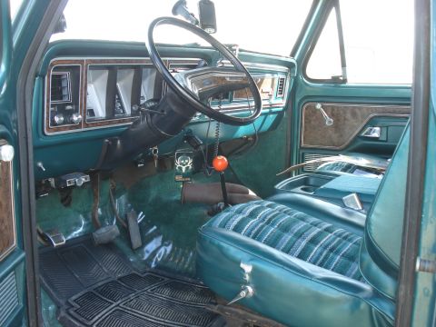 1979 Ford Bronco - The interior of a 1979 Ford Bronco shows its distinctive plaid seat upholstery and wood grain accents.